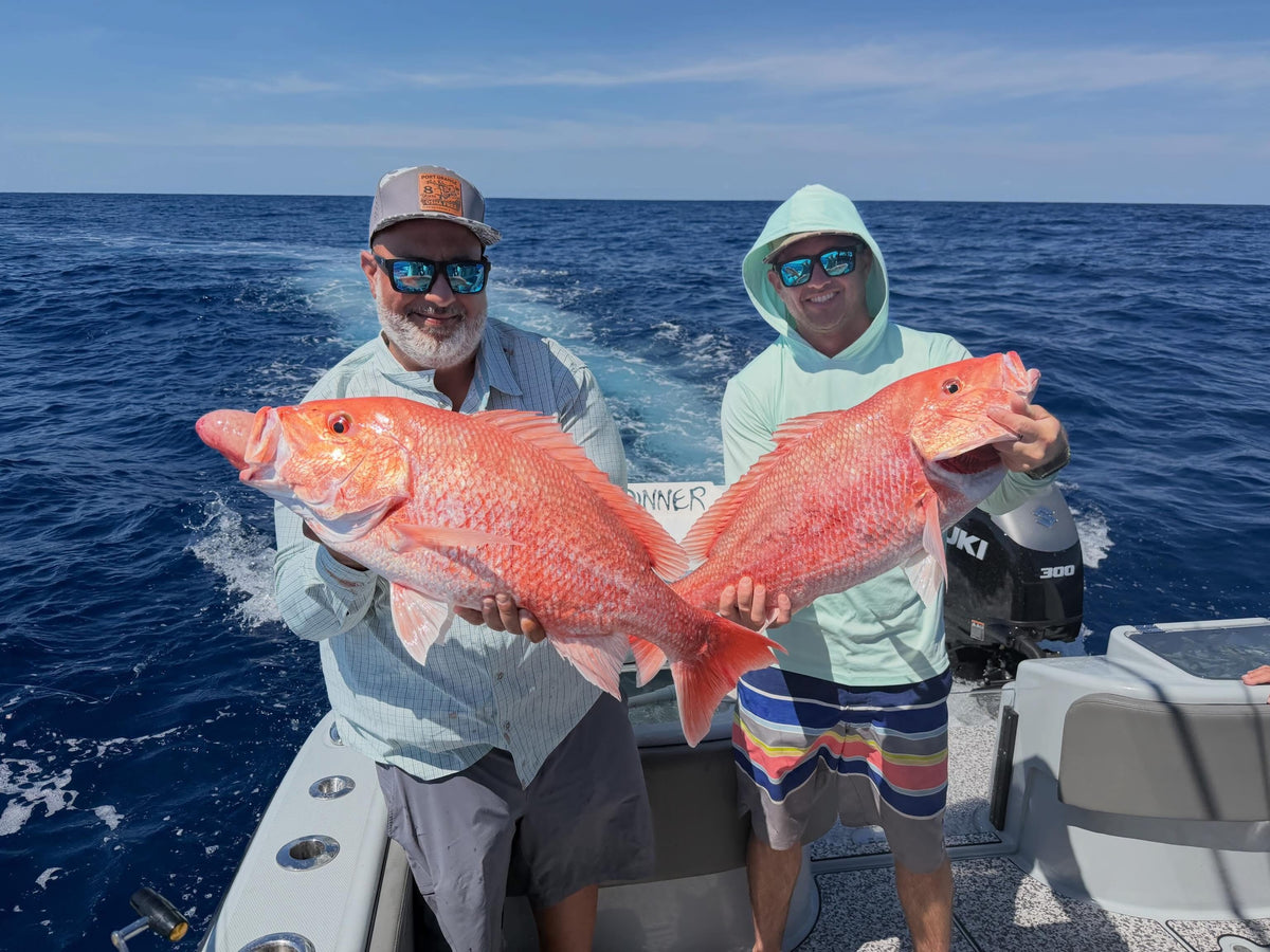 Two men on DMFD Life Insetta 35IFC Charter Fishing boat holding large red snapper in the ocean from a DMFD Life fishing charter out of ponce inlet, FL