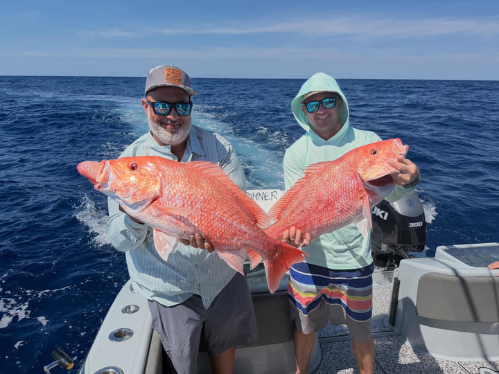 Two men on DMFD Life Insetta 35IFC Charter Fishing boat holding large red snapper in the ocean from a DMFD Life fishing charter out of ponce inlet, FL