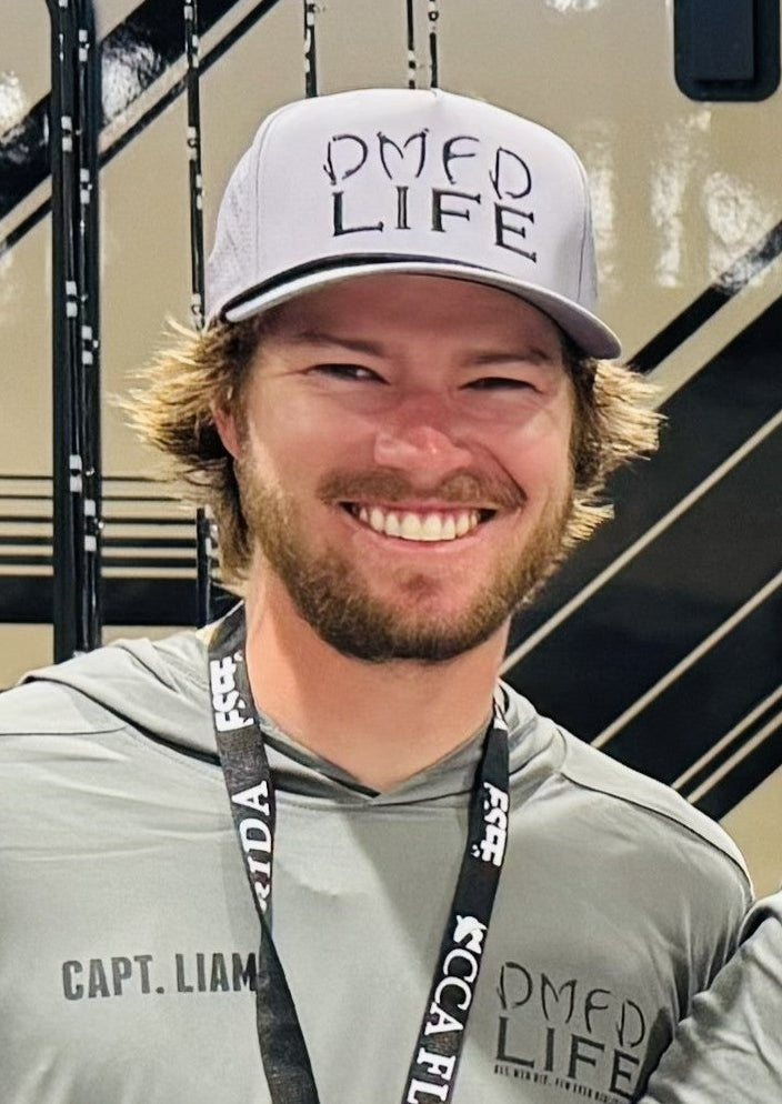 Person wearing a cap and hoodie with 'DMED LIFE' text, standing indoors.