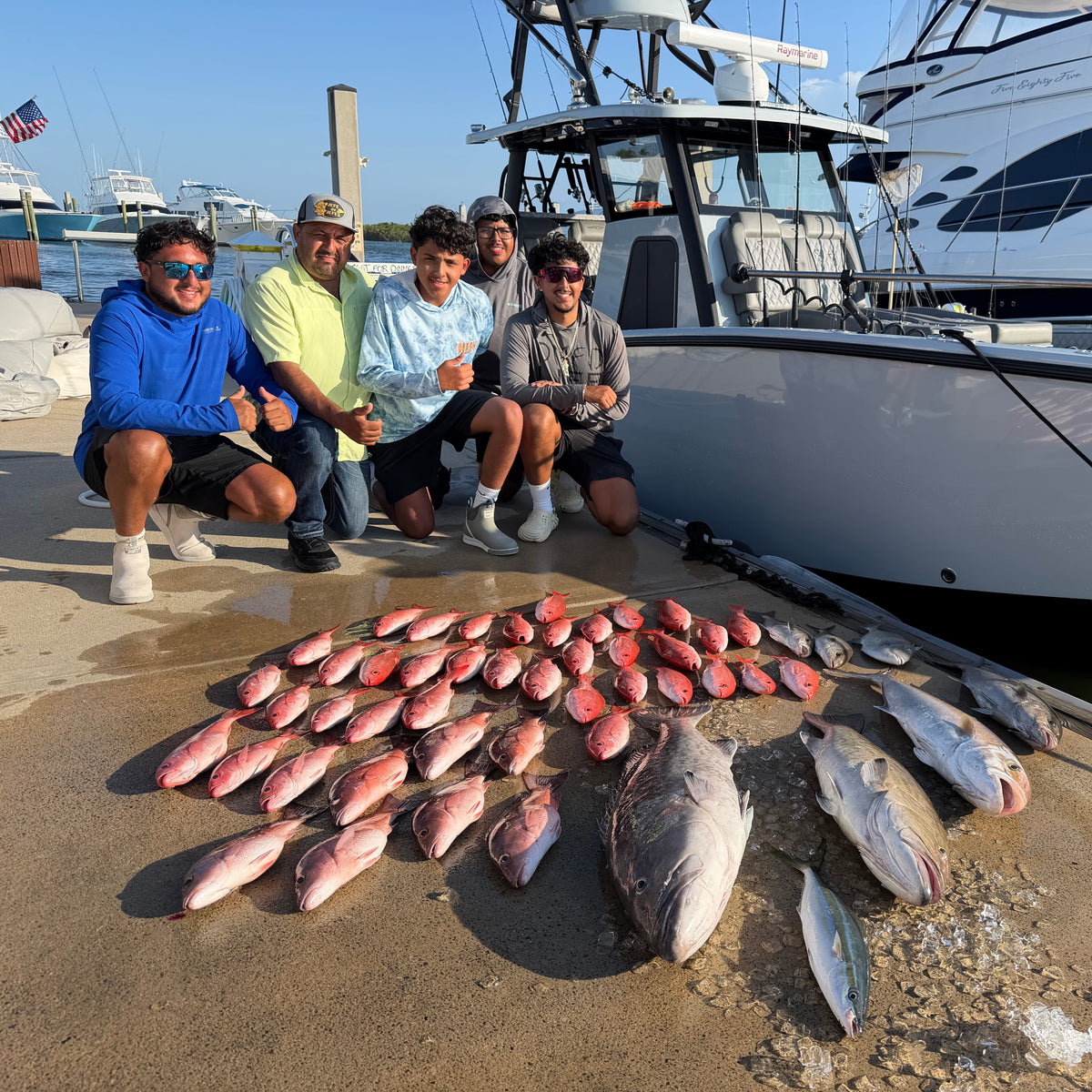 Five men posing on a boat dock with a large catch of fish laid out in front of them next to the DMFD Life Insetta 35IFC "Forty 1" Charter Fishing boat