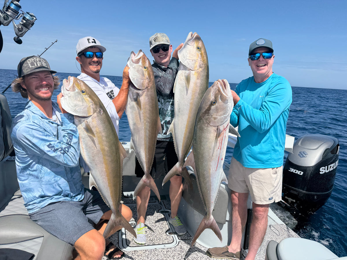 Four men standing on the DMFD Life Insetta 35IFC "Forty 1" Charter Fishing boat in a boat on the water holding four large fish. They are wearing hats, sunglasses, and casual fishing attire.
