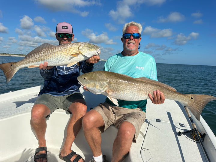 DMFD Life East Cape Charter Boat guests on the water holding large fish with a clear sky and the Atlantic ocean background