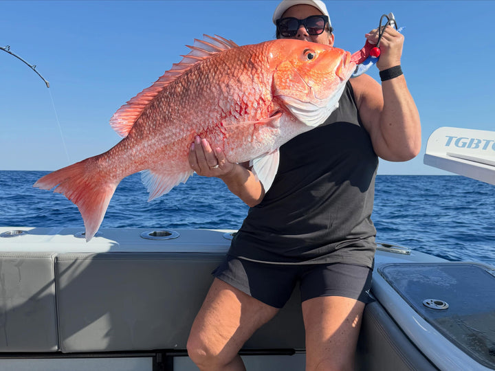 Person holding a large red snapper a Insetta 35 IFC catamaran from DMFD Life Charters with blue water and sky in the background