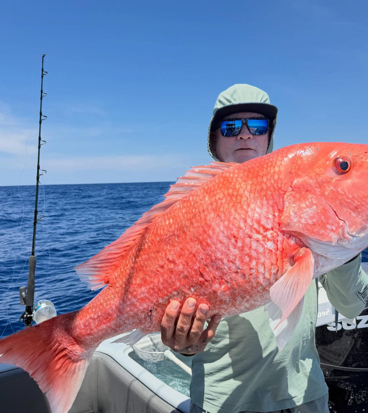 Person holding a large red fish on a DMFD Life Insetta 35IFC Charter Fishing  boat with ocean and sky in the background