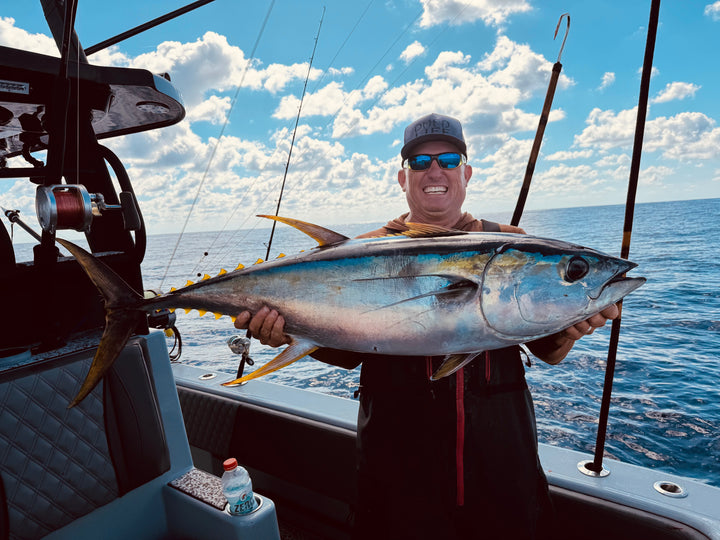 Robert Arrington holding a large tuna on DMFD Life Insetta 35IFC "Forty 1" Charter Fishing boat with a blue sky and ocean background